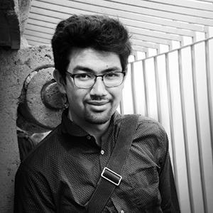 Black and white portrait of a young man with short hair and square rimmed glasses. 