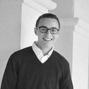 Black and White portrait of a young man with short hair and square rimmed glasses. 