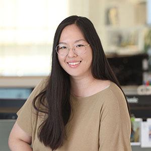 A woman with long black hair, wearing a tan shirt. 