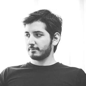 black and white headshot of a man with dark hair and a beard wearing a black shirt