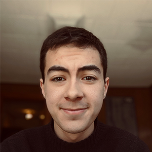 headshot of man with short dark hair and ceiling in background