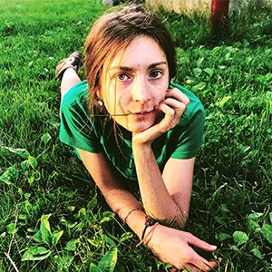 headshot of woman in green shirt laying forward on grass