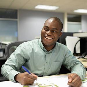 young man wearing a green shirt seated at a desk drawing