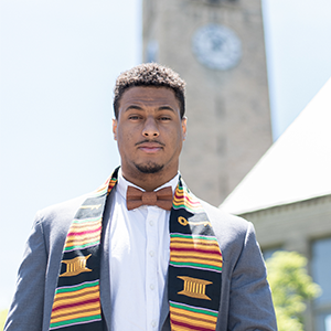 man in suit with graduation stole with building tower in background