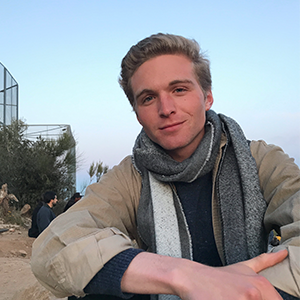 headshot of man with gray scarf with blue sky background