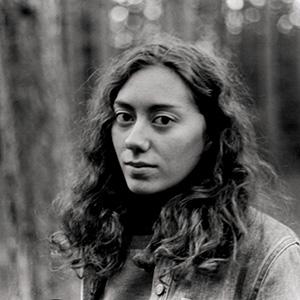 black and white headshot of a person with long dark hair take against a forest background