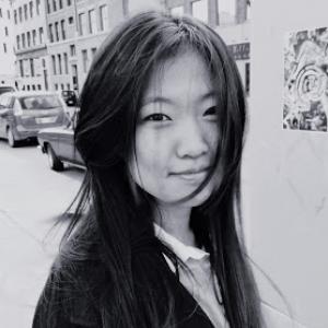 headshot of a woman with long dark hair and a street scene behind her