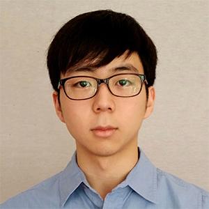 young man with dark hair and glasses in a blue shirt