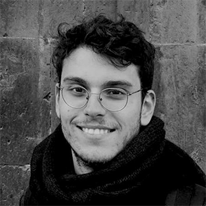 Black and White portrait of a young man with short hair and wire rimmed glasses. 