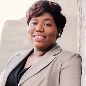 headshot of woman in beige suit and black shirt