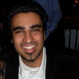 young man with dark hair and beard wearing a white shirt and dark blazer