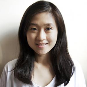 headshot of young woman with dark hair in front of a white wall