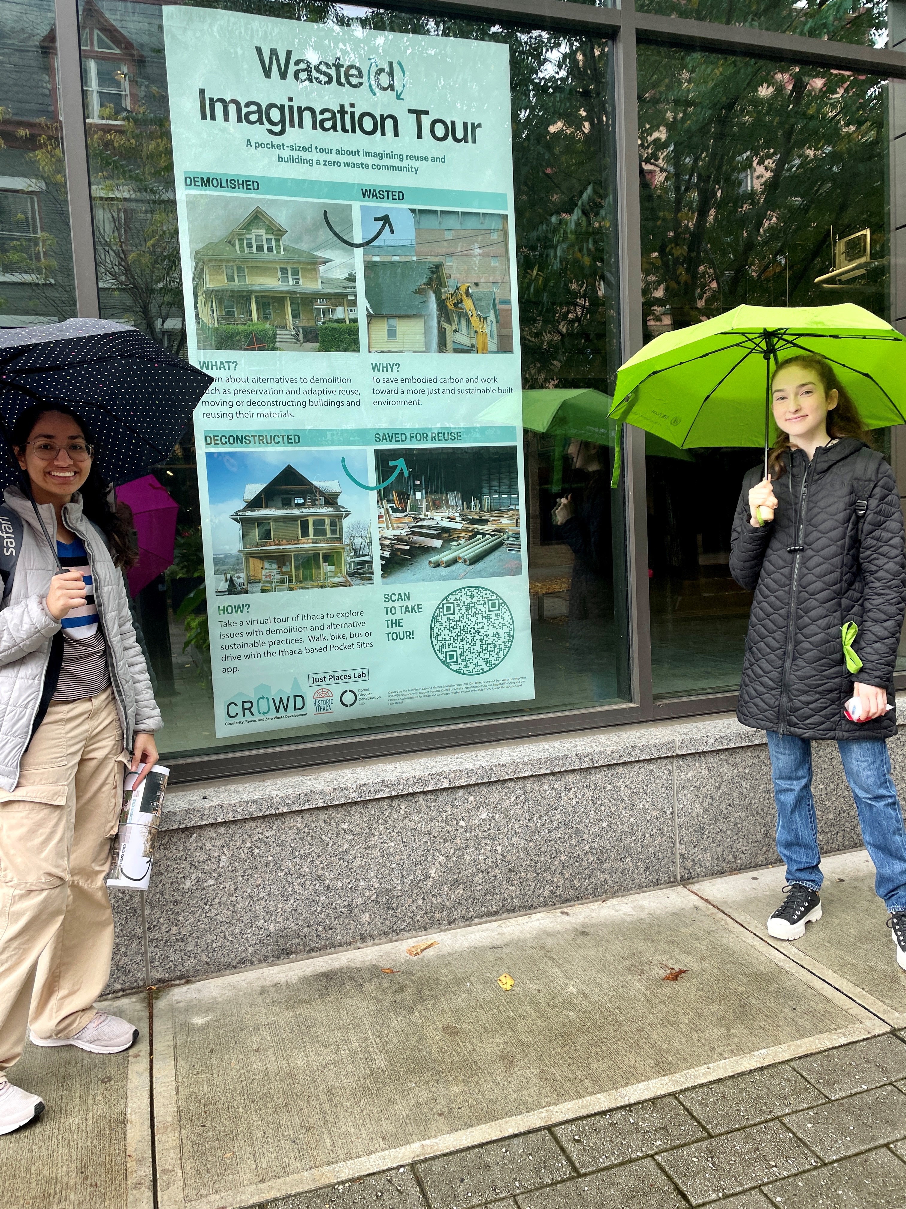 two students standing in front of a storefront window in the rain