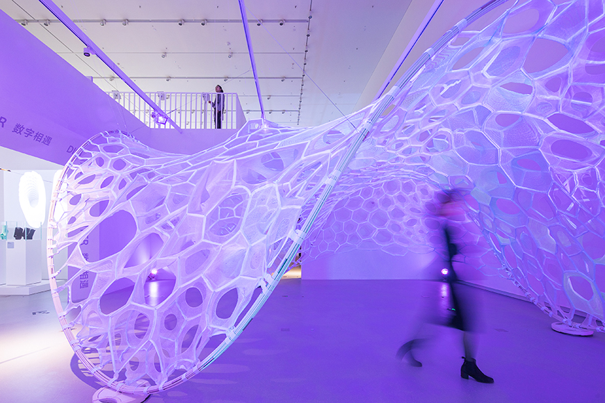 Purple floor and lighting with a curved white mesh sculpture that spans floor to ceiling.