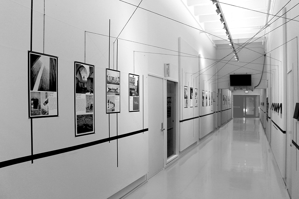 Hallway of the Architecture Department at Cornell University lined with infographics connected with black string