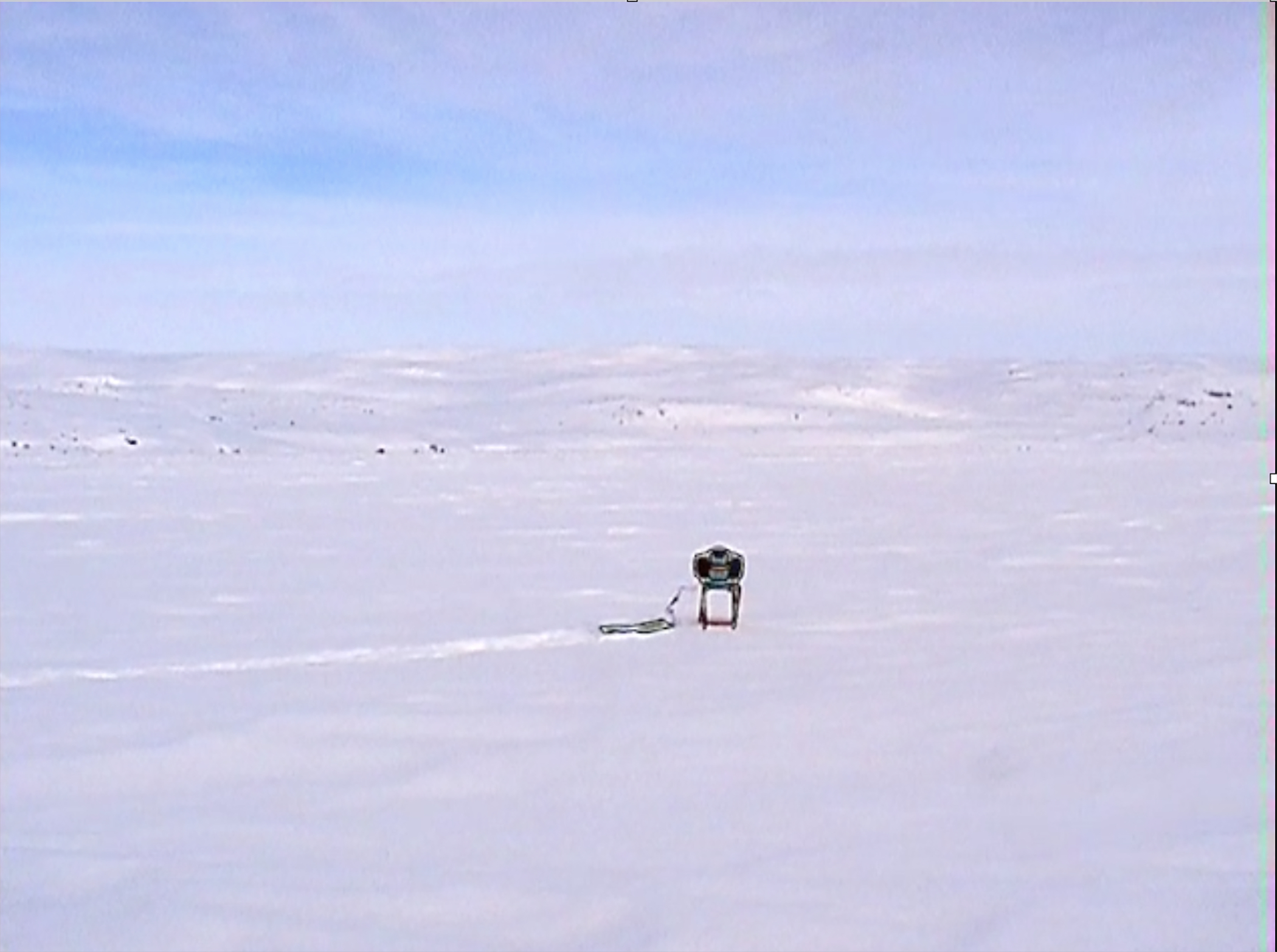 Barren winter landscape with blue sky horizon and a small robotic structure in the center of the image