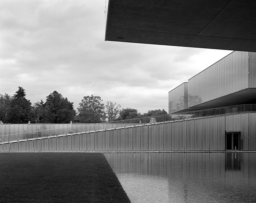 Modern building surrounding a reflective pool in black and white.