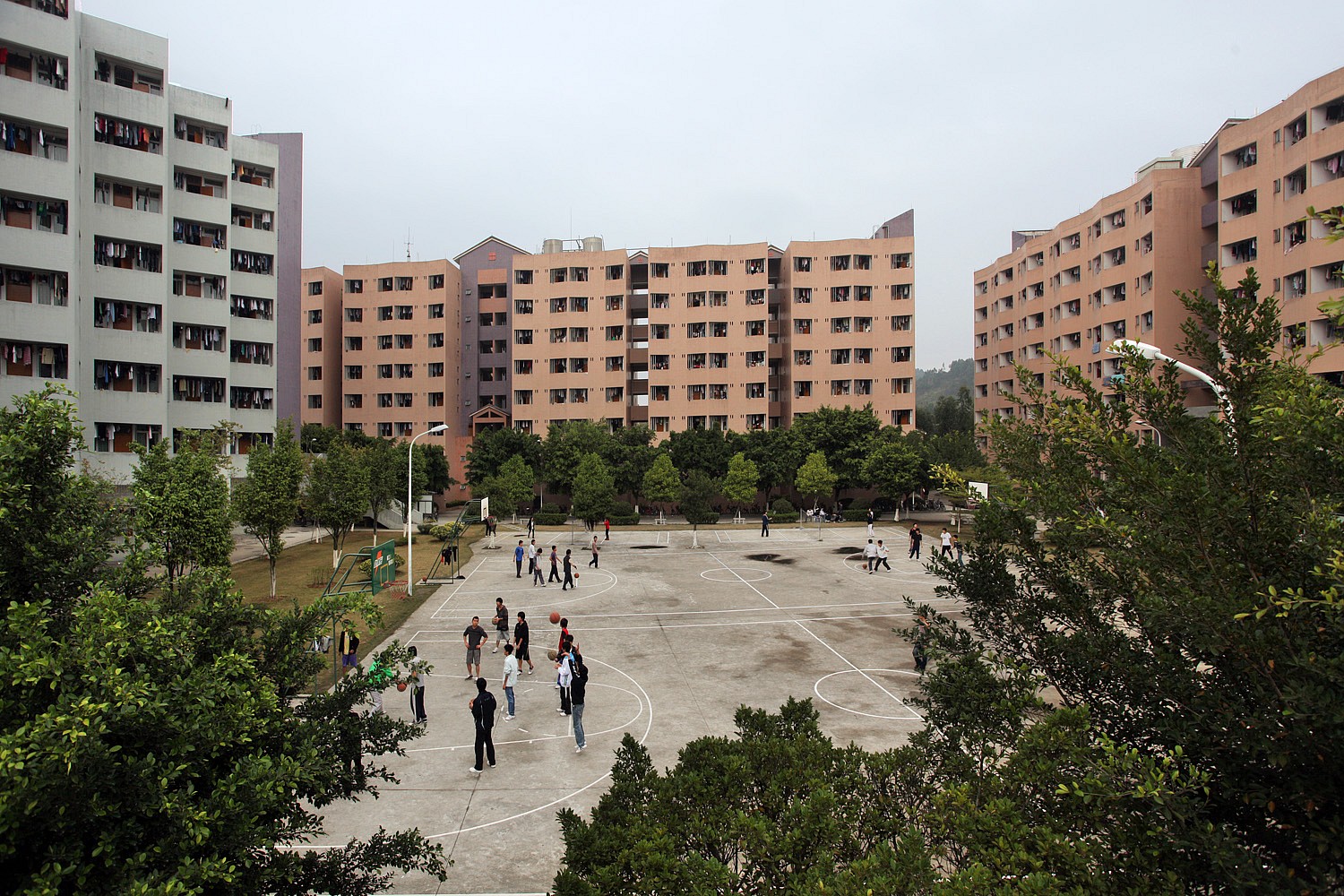 View of grey and brick-colored dorm building exteriors and basketball court.
