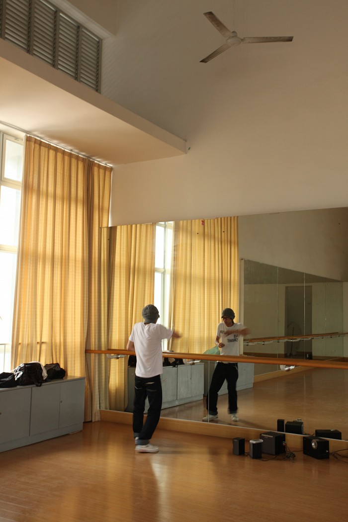 A male student dances in front of a large mirror.
