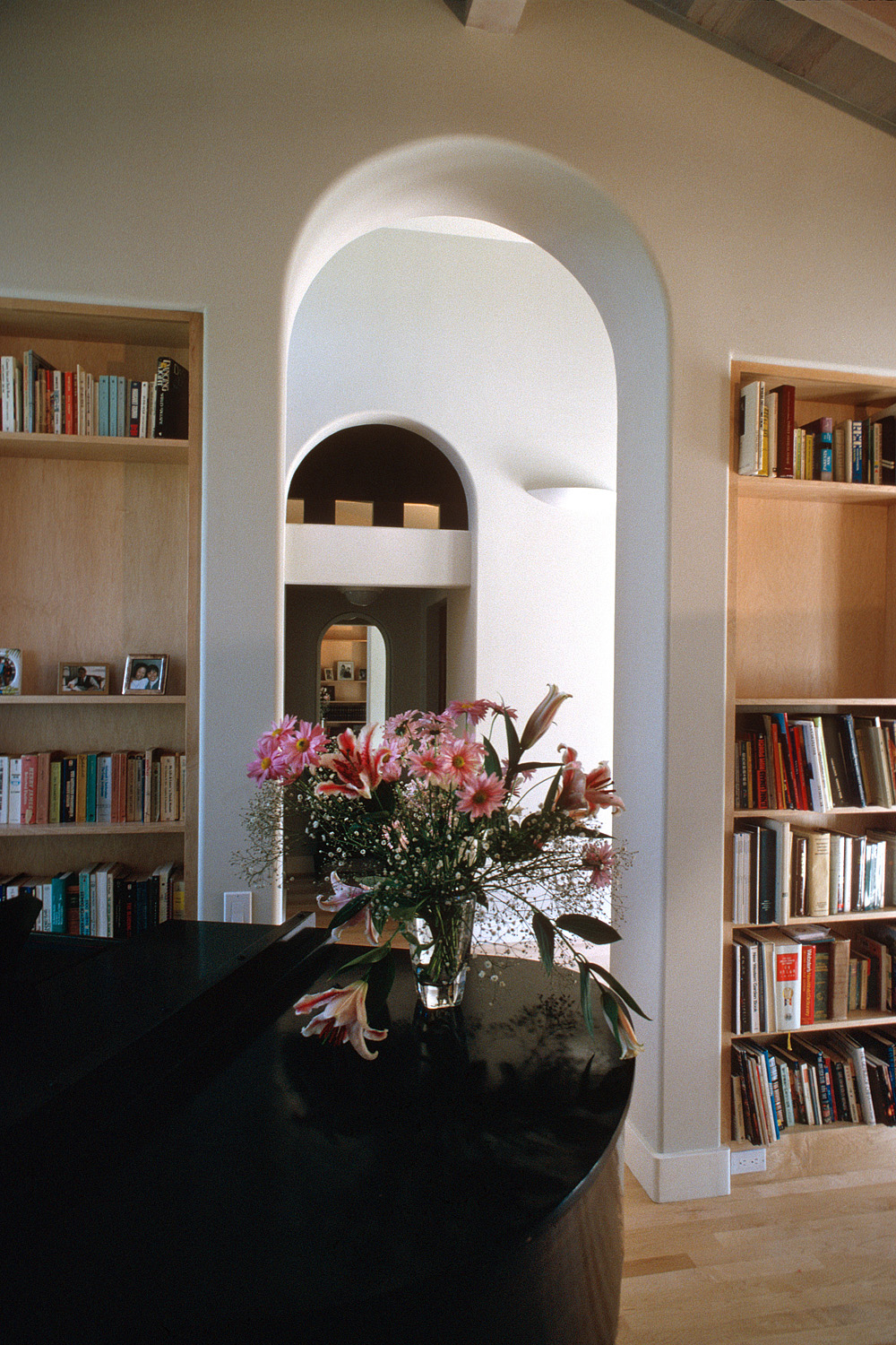 A vase of pink flowers on a table in the library.