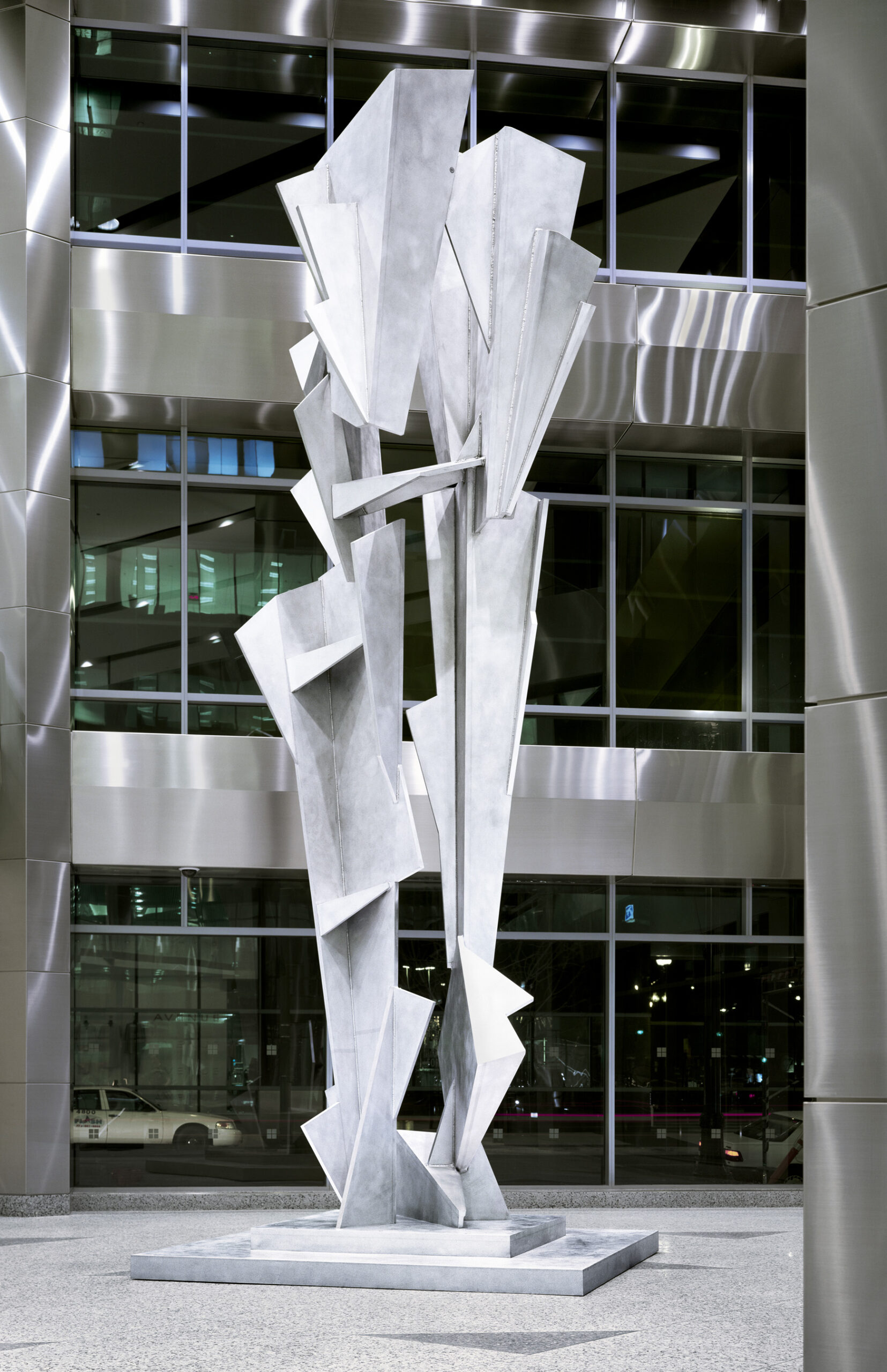 a large abstract silver metal construction in front of a building