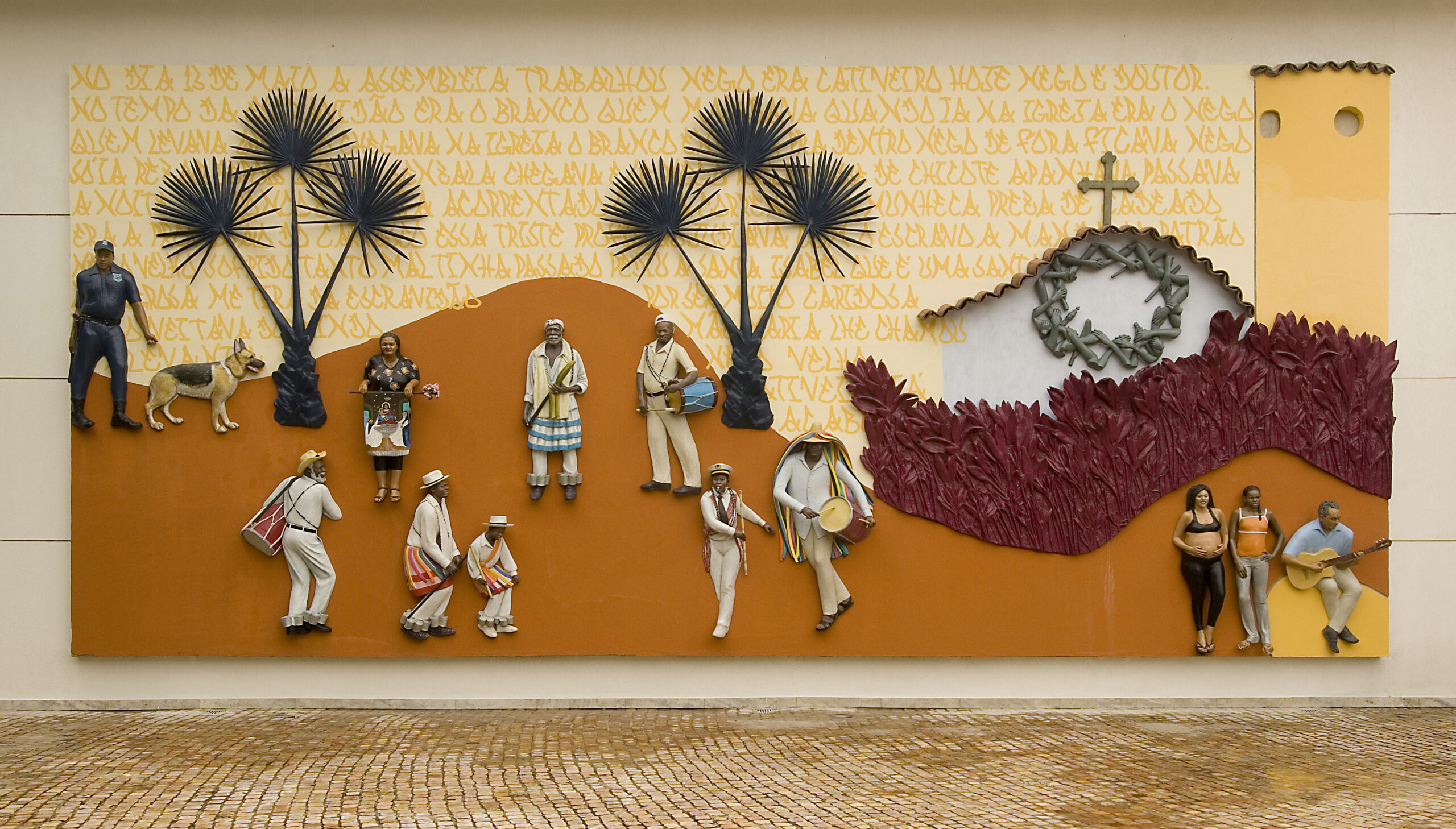 sculpture relief on the wall of people on a rolling landscape in oranges and yellows