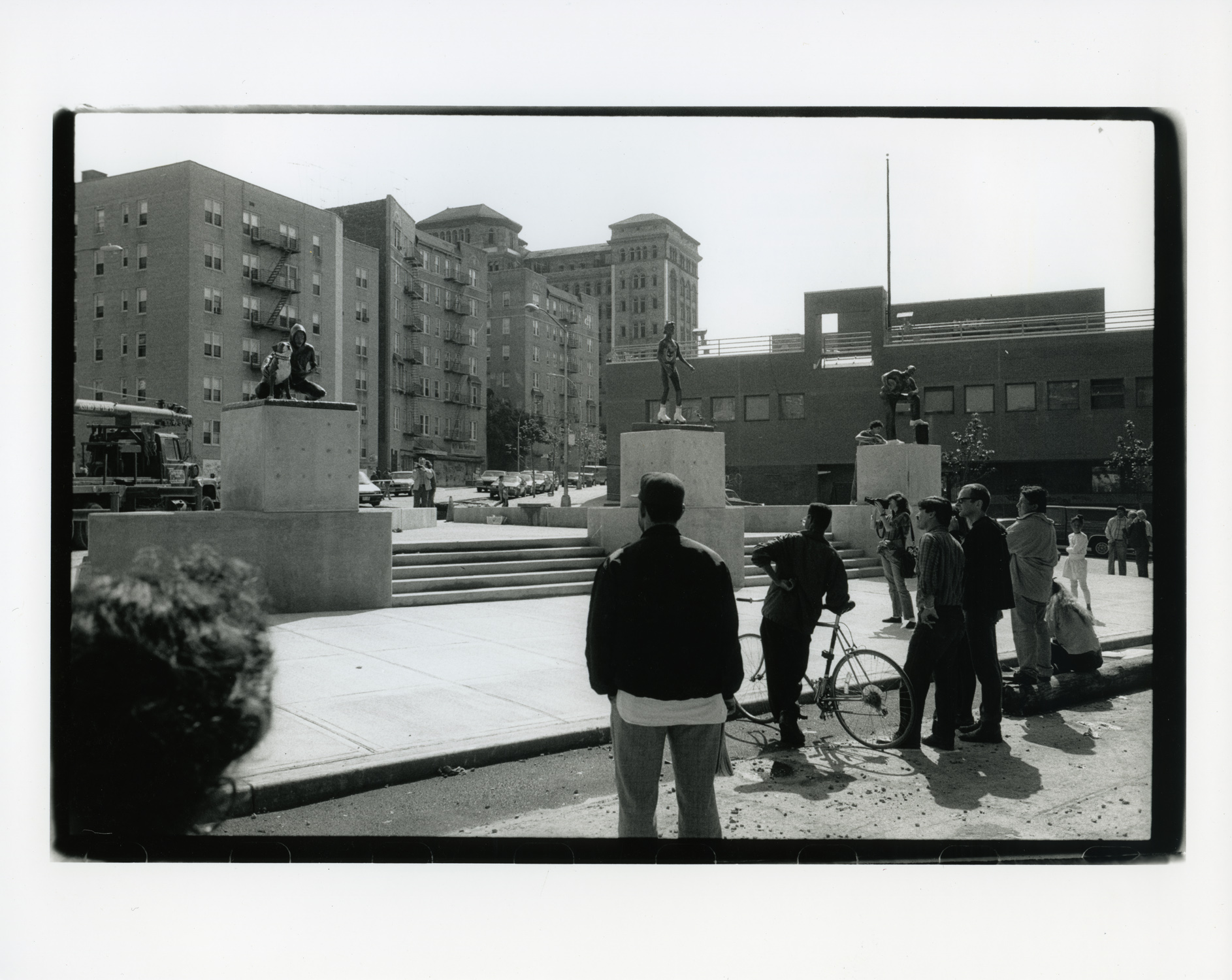 black and white photo of people looking at a sculpture on a pedestal outside
