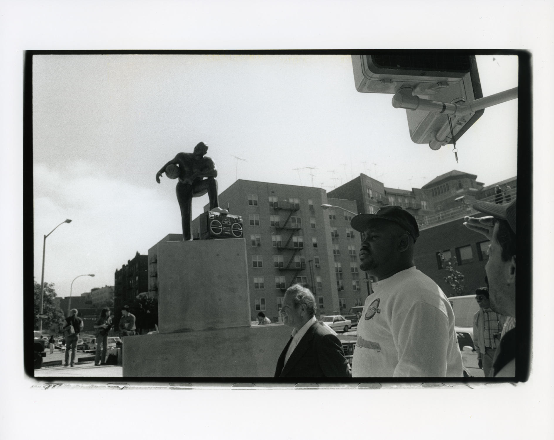 Black and white photo of people looking at sculptures outdoor in an urban area