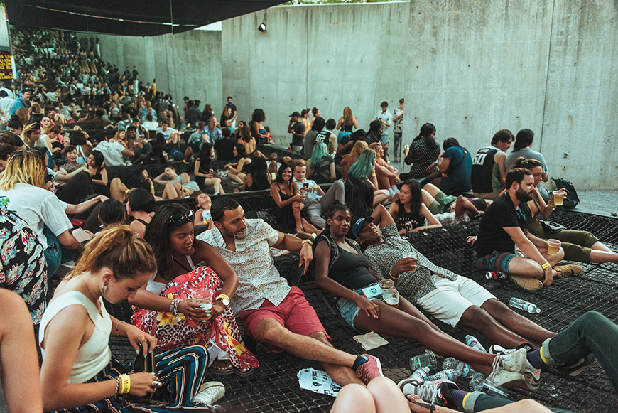 A large group of students sitting on bleachers surrounded by concrete walls.