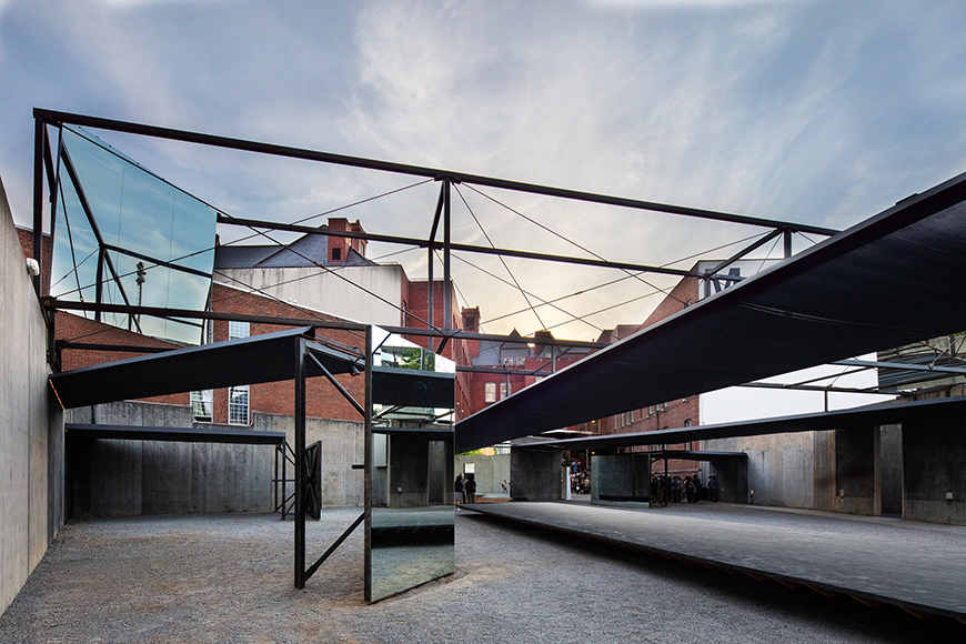 A metal outdoor canopy with mirrors positioned in an urban setting.