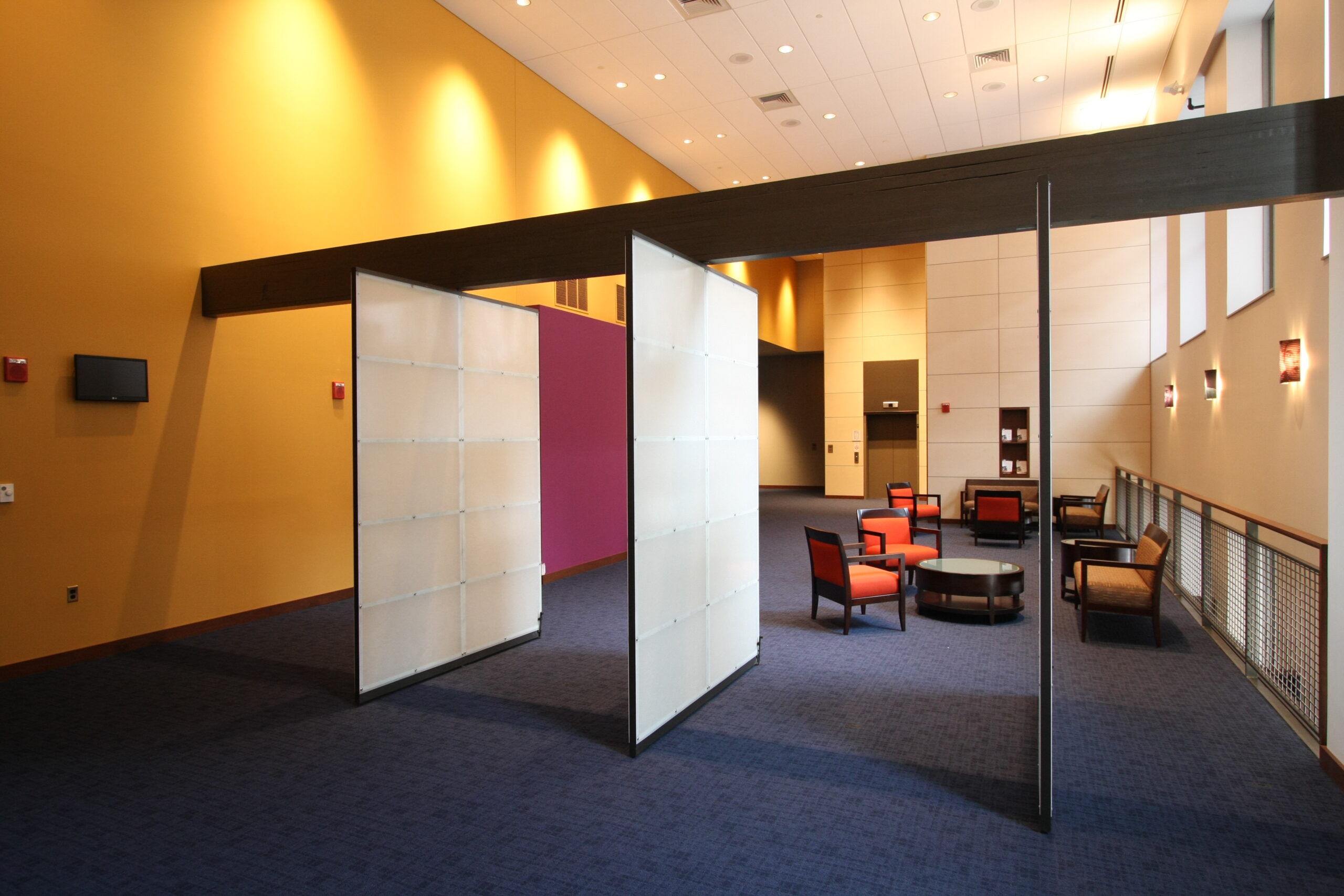 A wide hallway with a meeting area and open space.