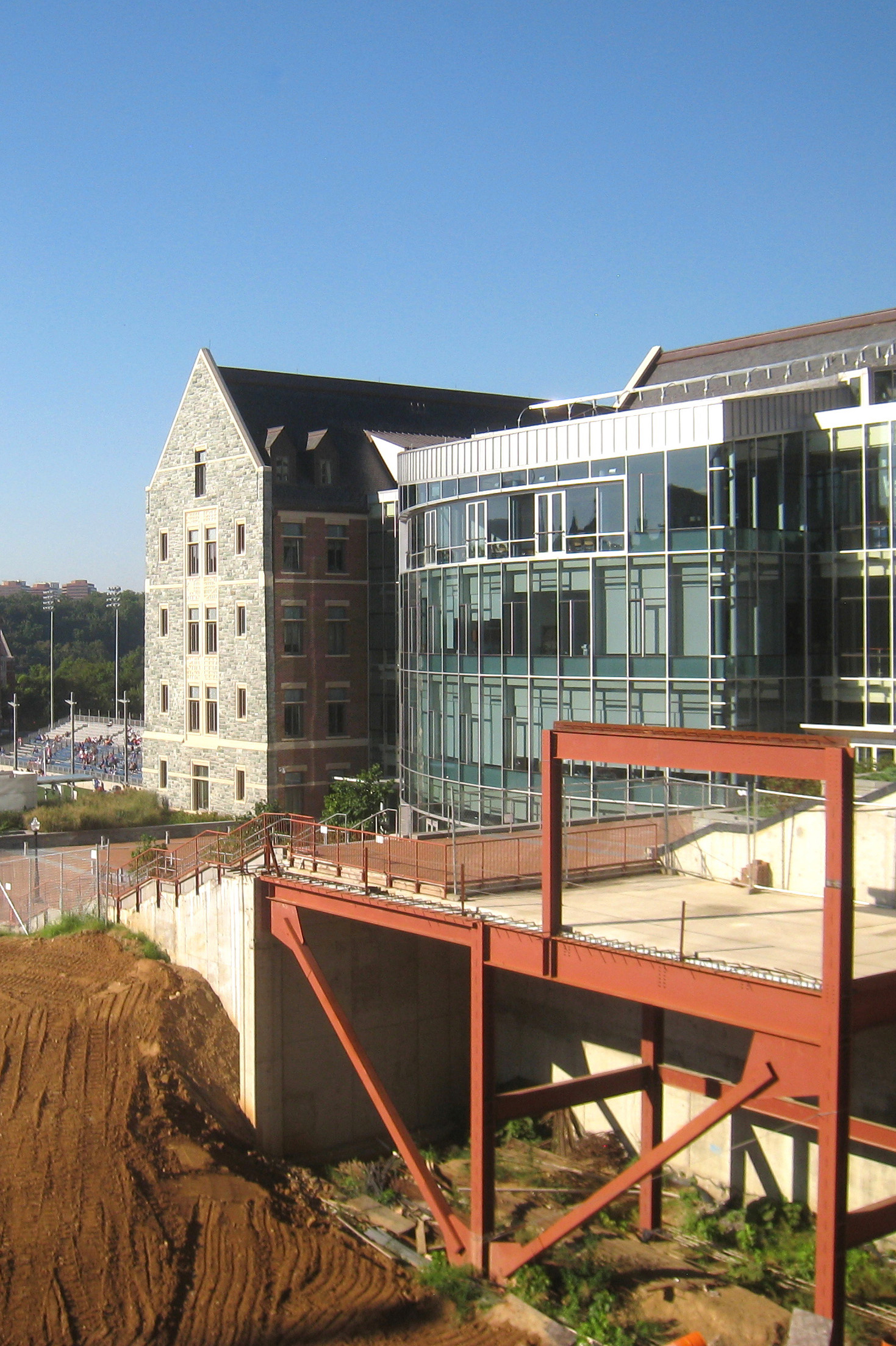 A construction site is set up in front of a building made of stone masonry and a second building with glass walls.