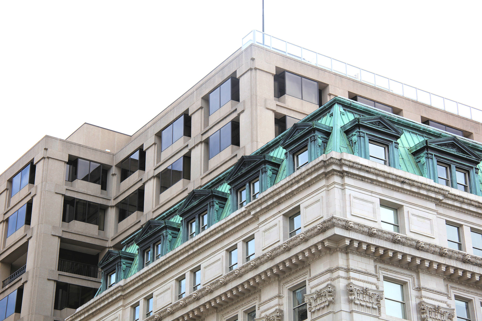 View of upper green facade on top of a multistory tan building.