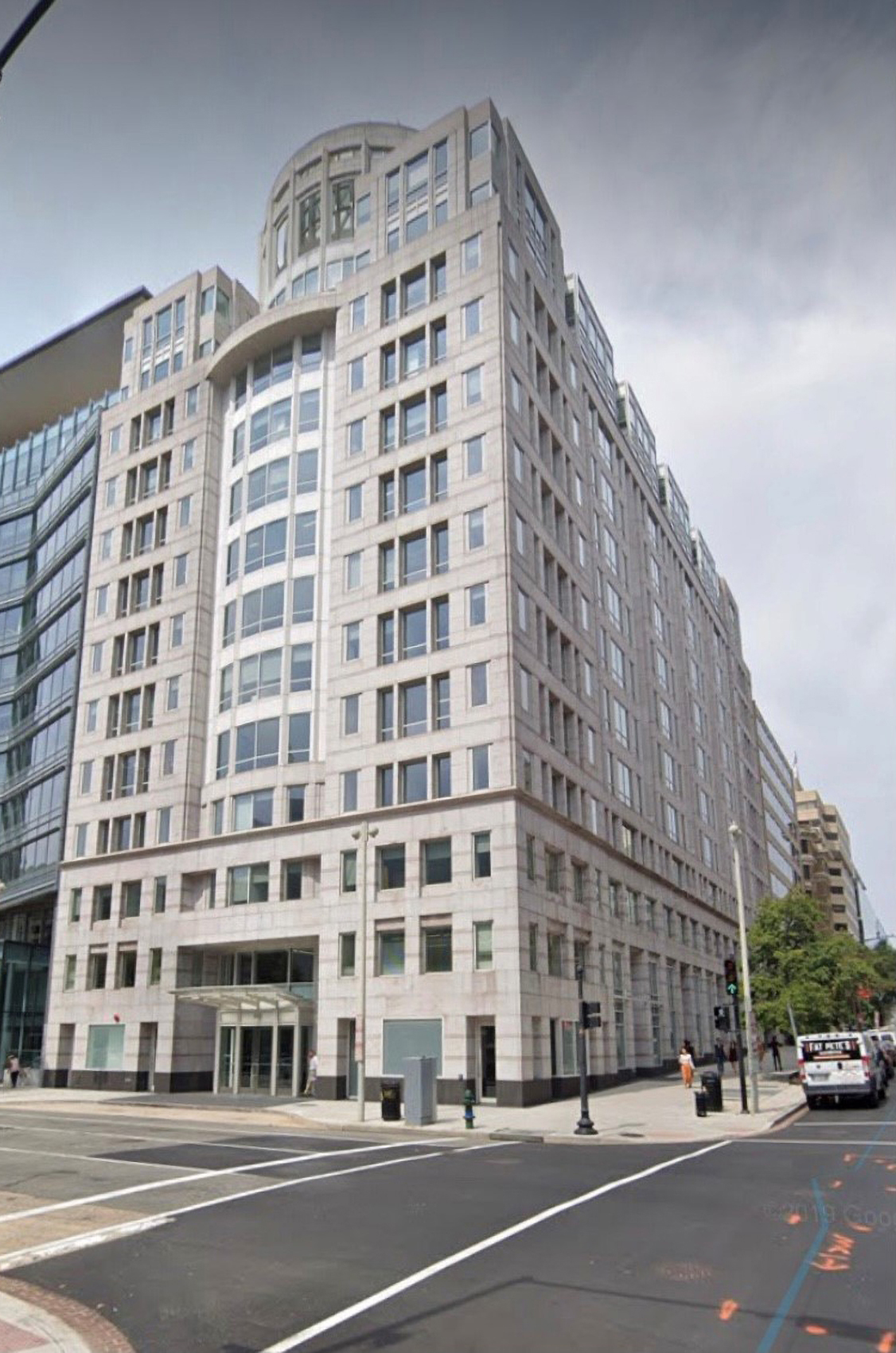 Photo shows the front and side of a tall, rectangular building as viewed from a low perspective looking up at the building.