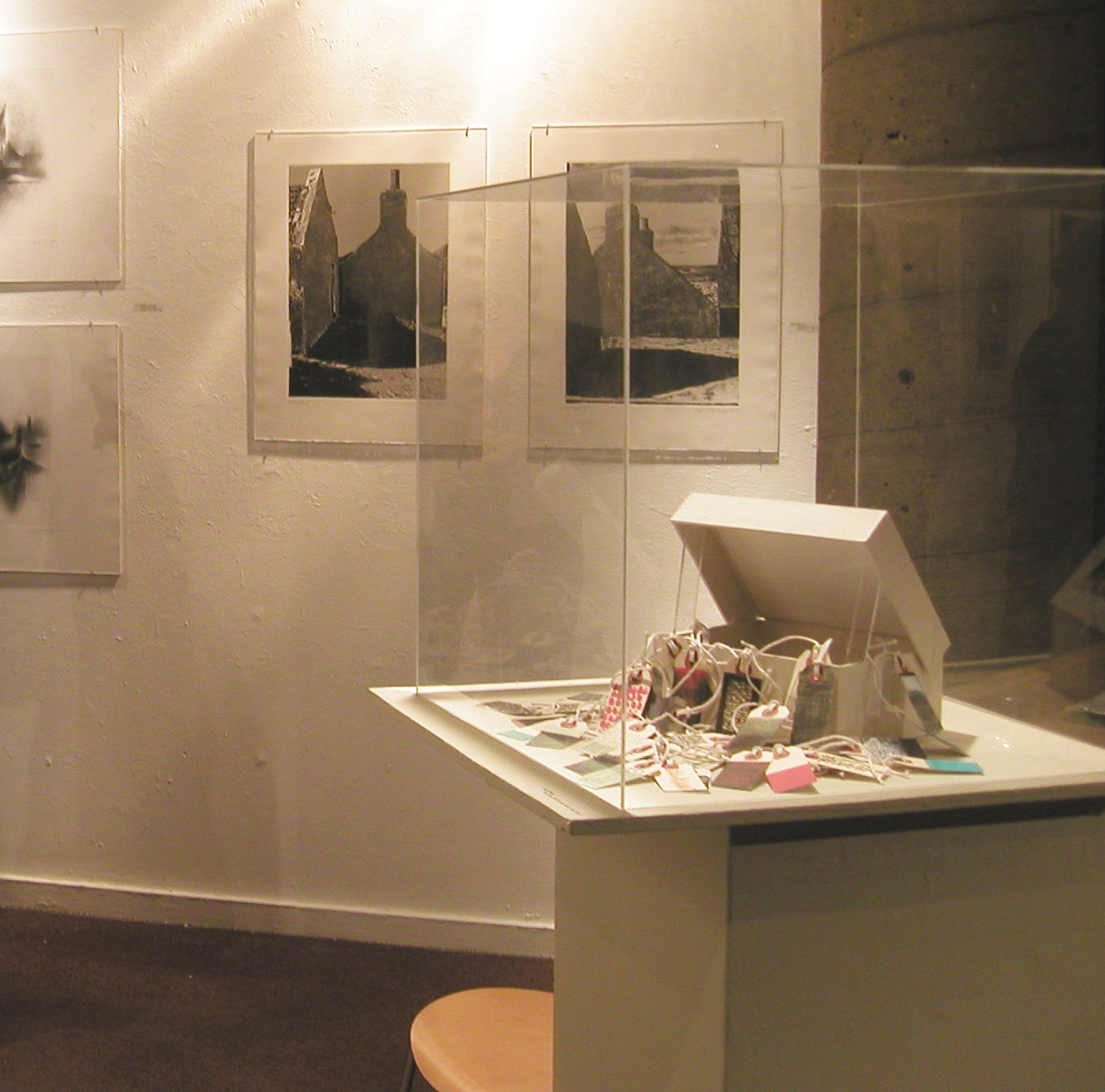 A display case houses gift tags and a box with an open lid. Art prints hang on the wall behind the display case.