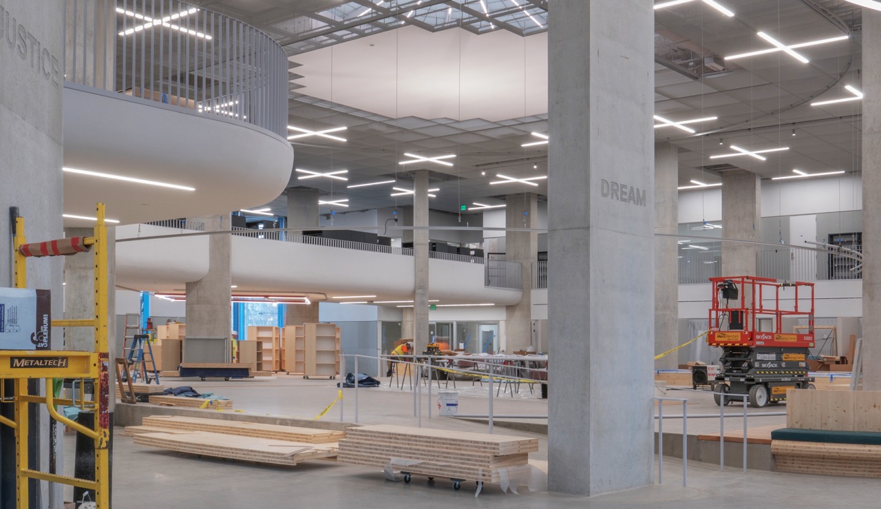 Interior view of library with benches in foreground and book stacks in background.