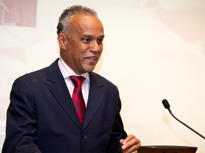 Photo of a middle-aged man dressed in professional attire, speaking at a podium.