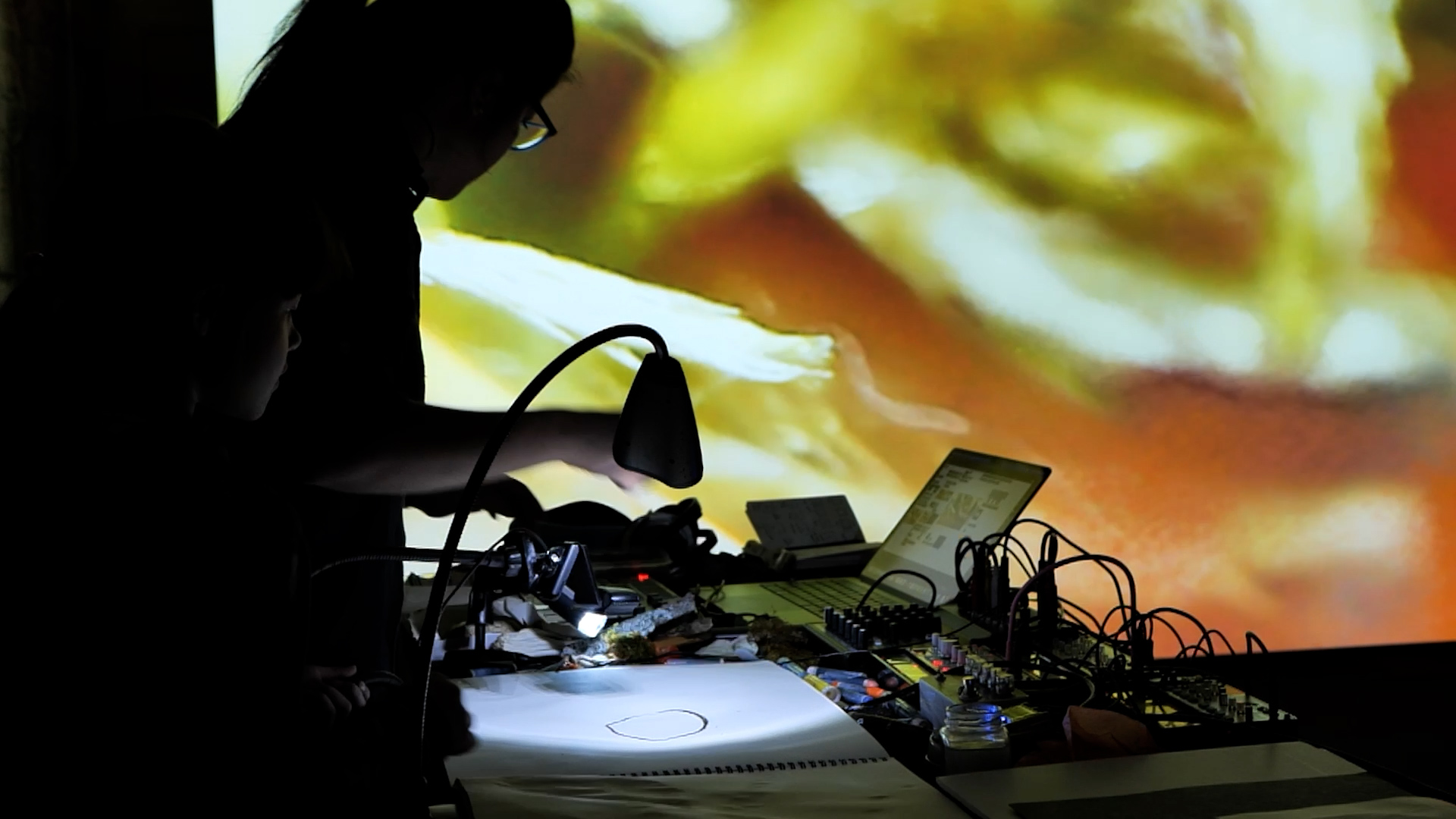 Silhouette of sound board and person operating the board with an abstract sunset image in the background