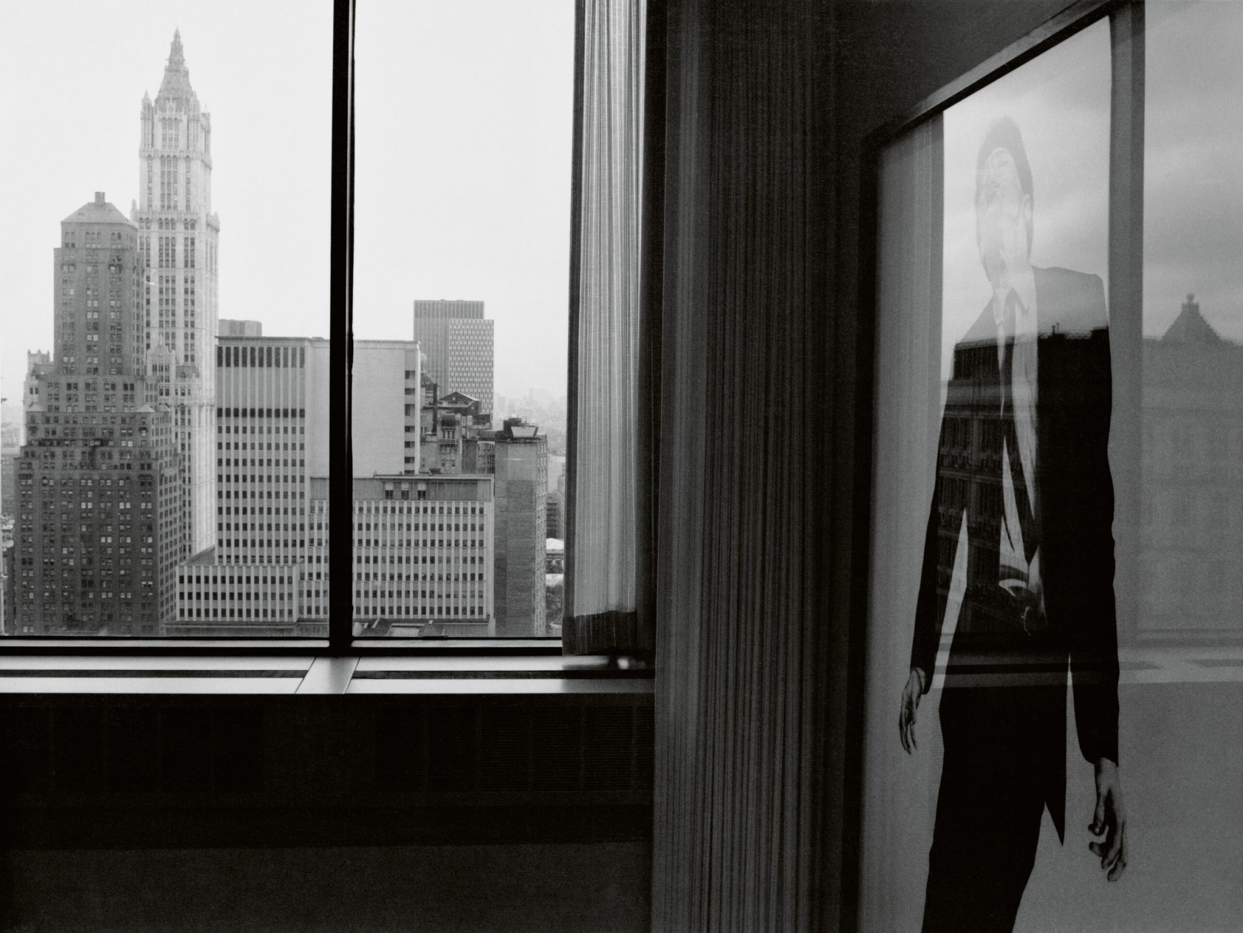image of the inside of a building with a Robert Longo photograph on one side and a window overlooking cities on the left
