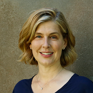 headshot of a woman with blond hair wearing a dark blue shirt