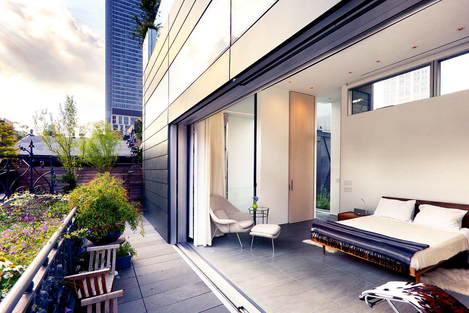 A wall of glass disappears to open the master bedroom to a garden terrace.