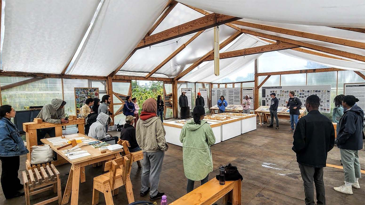 Students gathered in a large white tent examining models