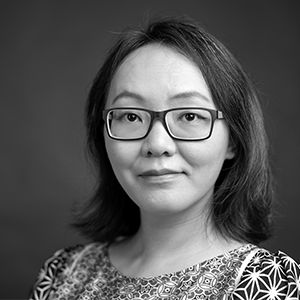 Person with shoulder-length dark hair wearing black-rimmed glasses