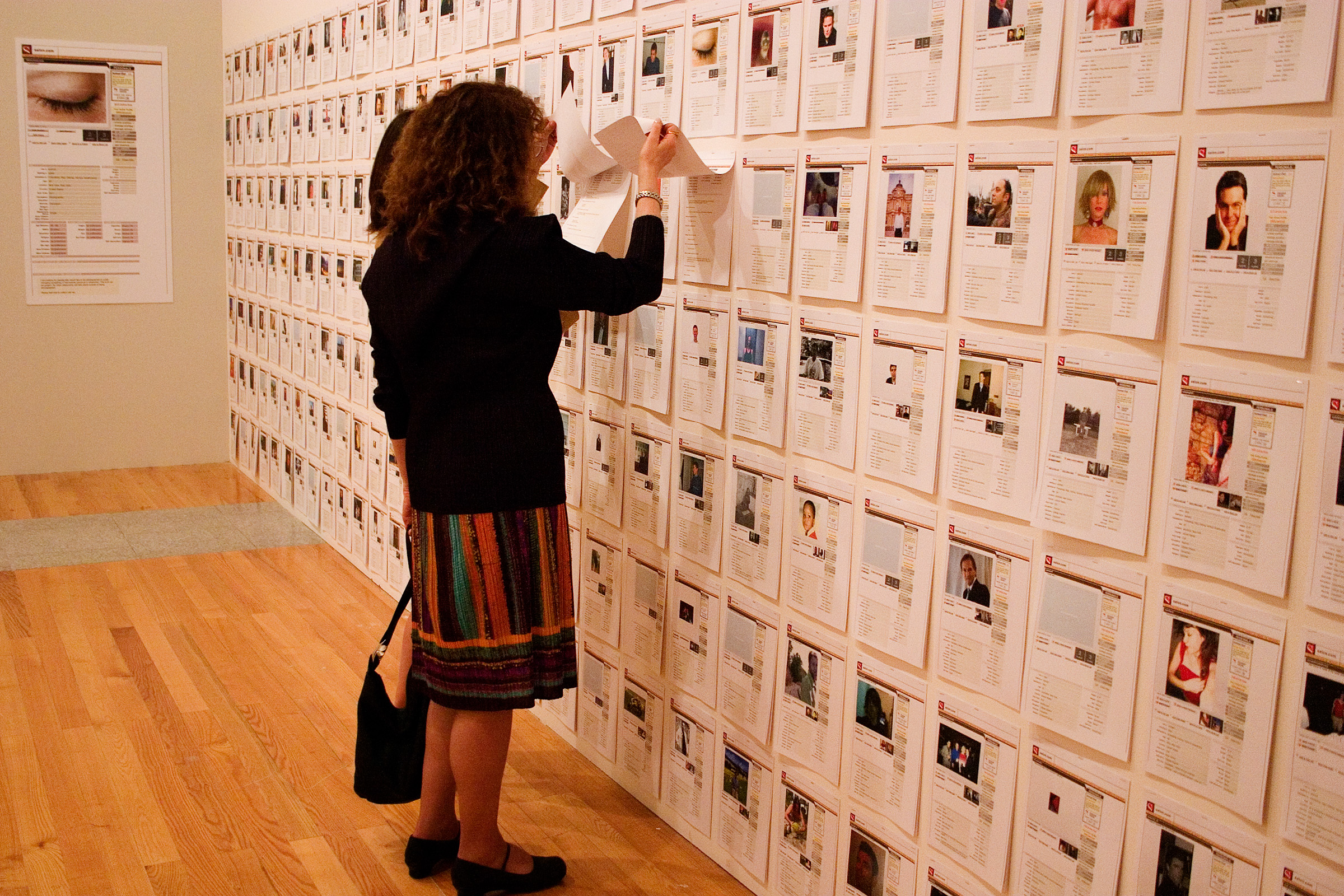 Two people examine papers displayed on a wall