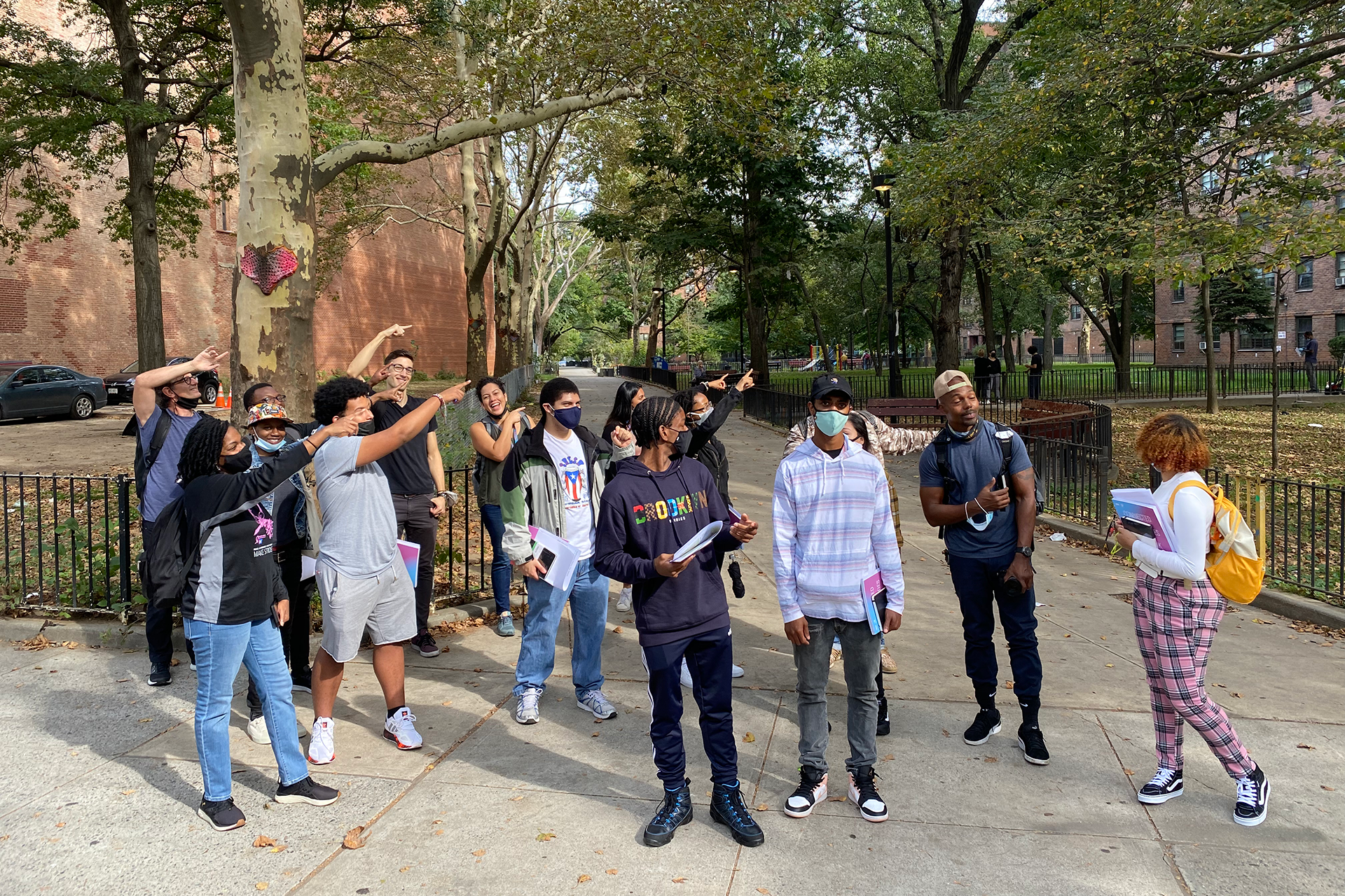 Group of people gathered on a city sidewalk smiling and pointing