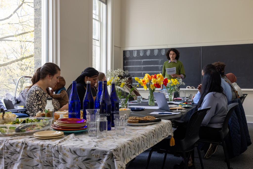group of people gathered around a table for a meeting with bright flowers at the center
