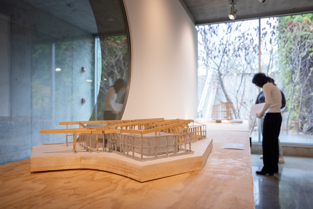 A building model on a table with two people in the distance.