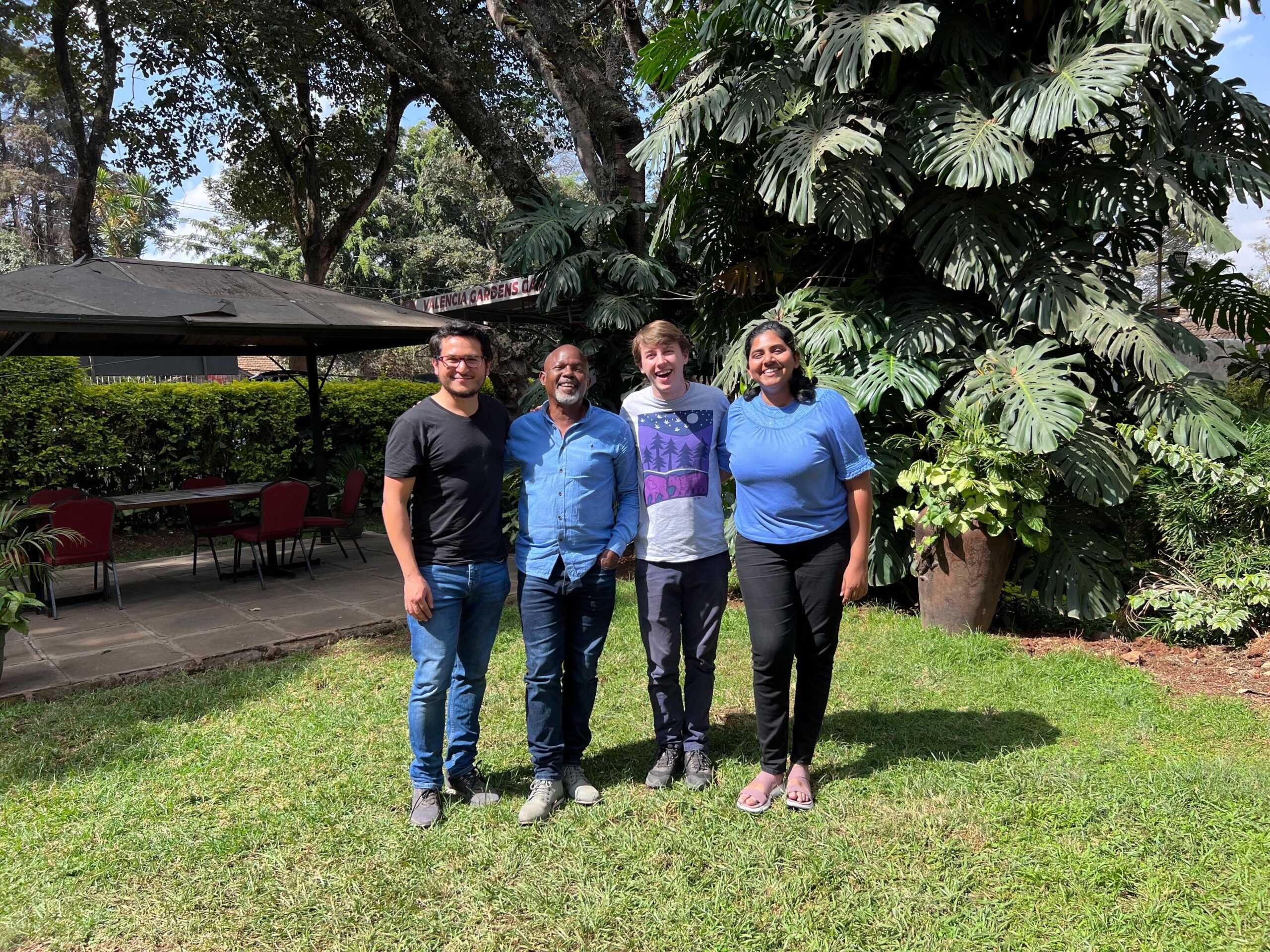 Group of people standing on a lawn with their arms around one another. 