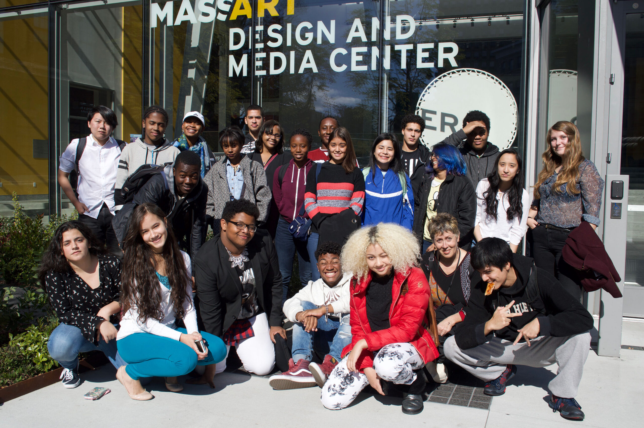 A group of young people pose for a photo in front of MassArt Design and Media Center