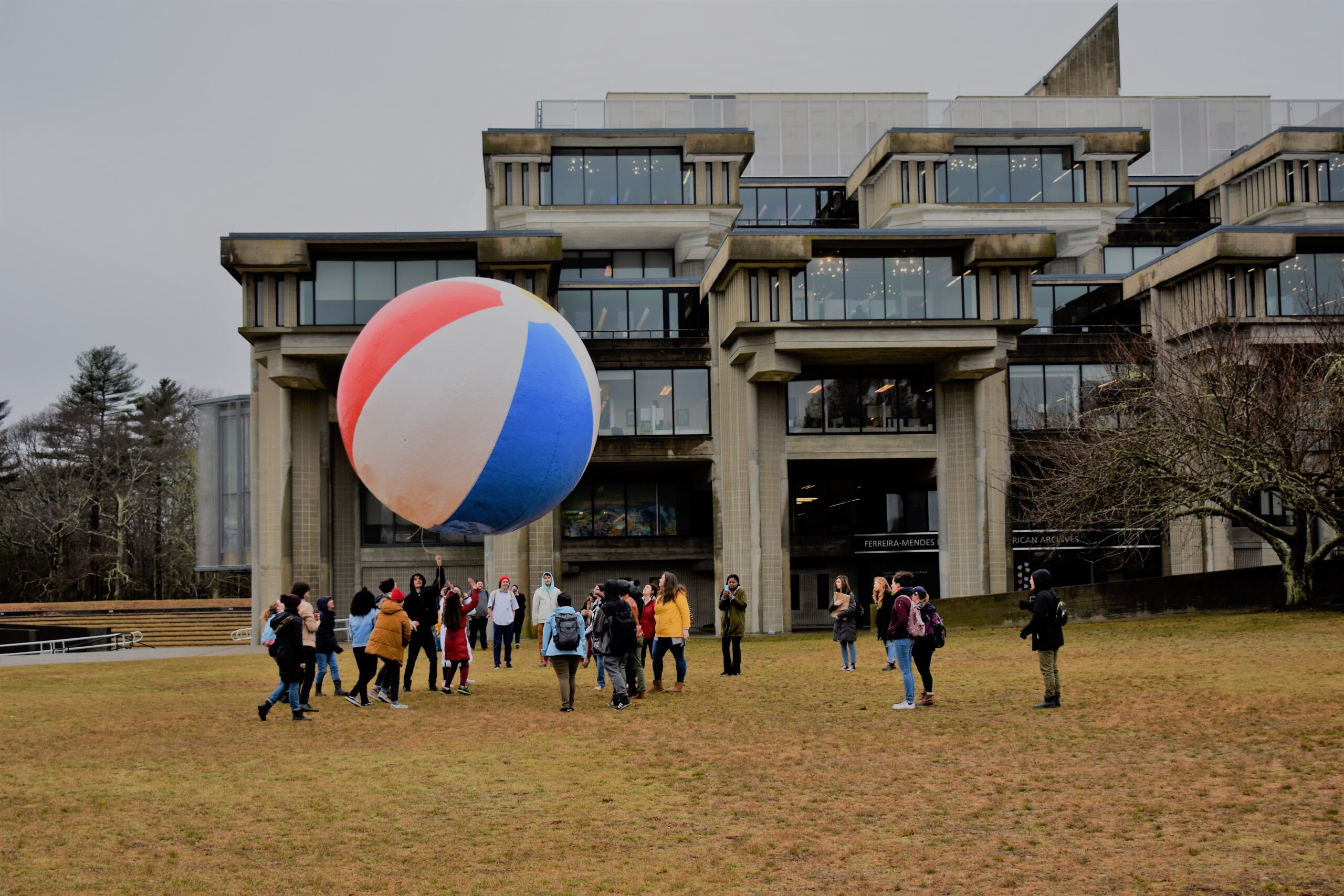 people playing with a large beach pall outside